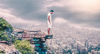 Man standing on cliff edge overlooking vast city skyline