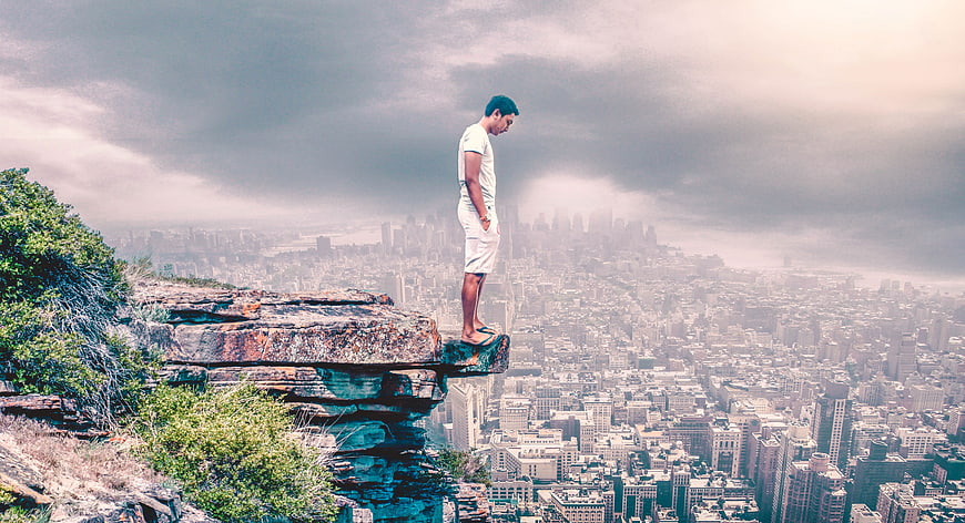 Man standing on cliff edge overlooking vast city skyline