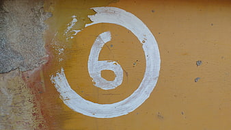 Hand-painted white number six on textured yellow wall