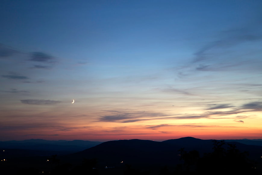 Crescent Moon Over Mountain Silhouette at Sunset