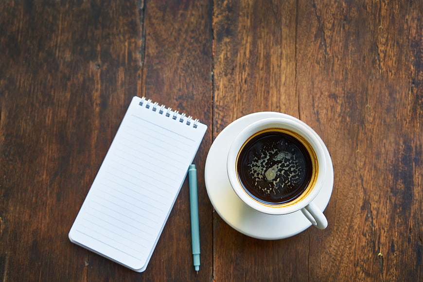 Top view of coffee cup and notebook on wooden table