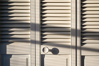 Minimalist White Slatted Door Detail With Strong Sunlight Shadows