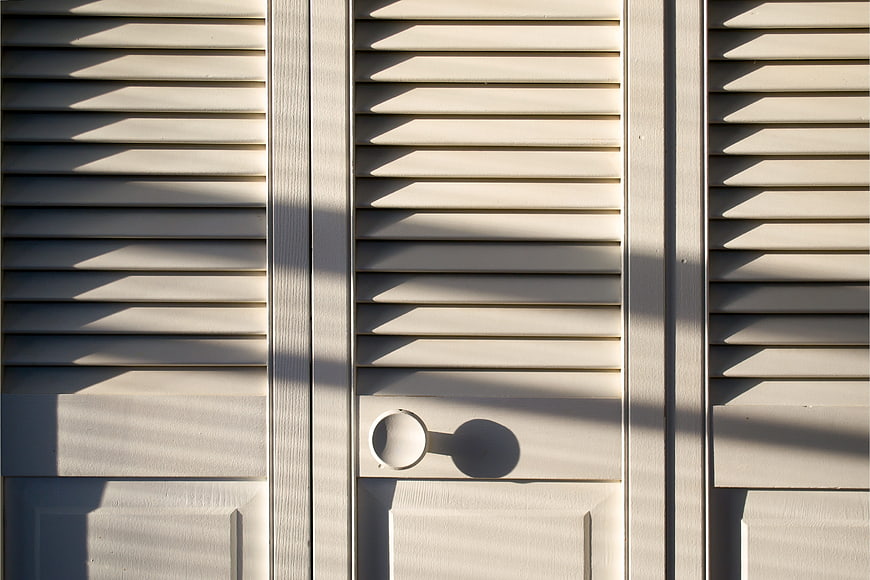 Minimalist White Slatted Door Detail With Strong Sunlight Shadows