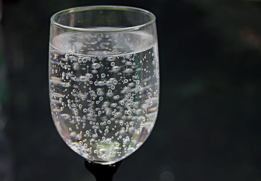 Close-up of a glass of sparkling water with rising bubbles