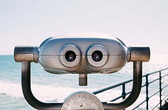 Close-up of silver tourist binoculars overlooking the ocean