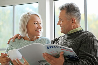 Happy Senior Couple Reading Magazine Indoors