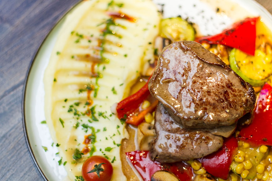 Close-up of grilled beef steak with mashed potatoes and vegetables