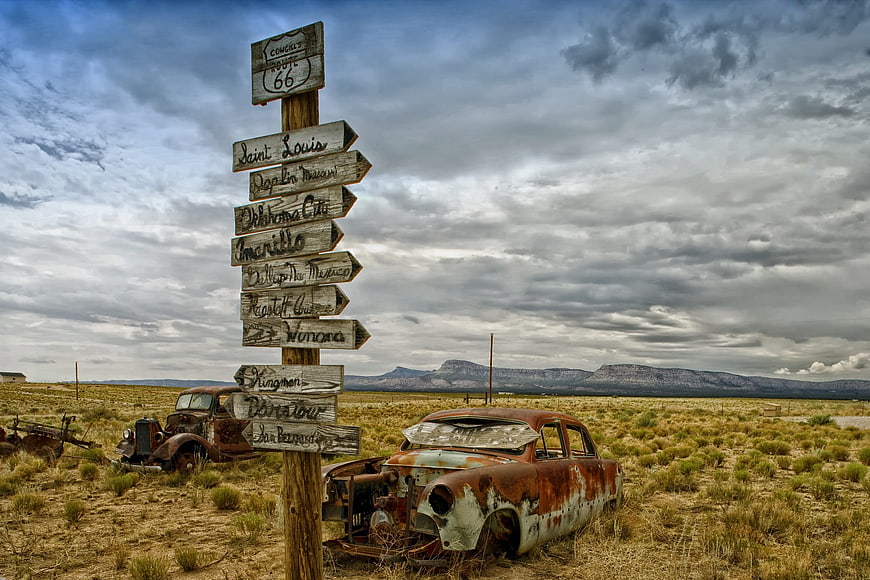 Rusty Vintage Cars and Route 66 Signpost in Desert Landscape