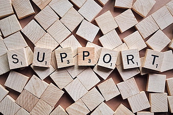 Wooden Scrabble Tiles Spelling Support on Scattered Background