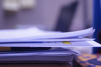 Close-up of stacked office papers with yellow sticky note