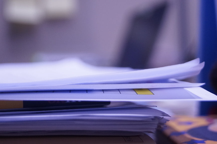 Close-up of stacked office papers with yellow sticky note