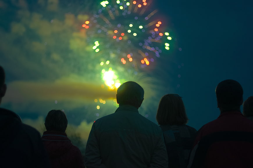 Silhouettes of People Watching Colorful Fireworks at Night