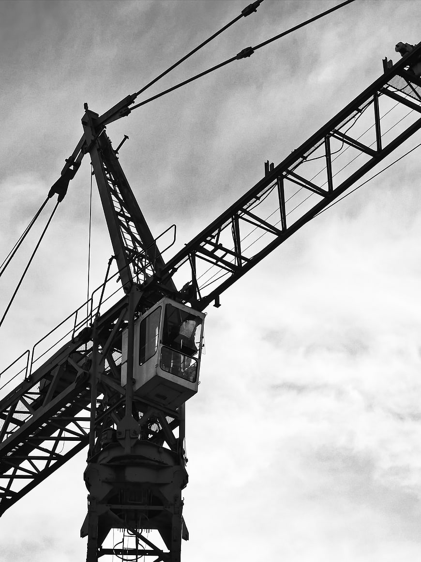 Black and white construction crane against cloudy sky
