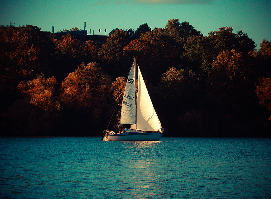 Sailboat on Lake with Autumn Trees Background
