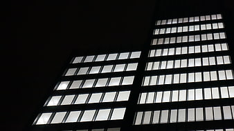 Low angle view of illuminated office building windows at night
