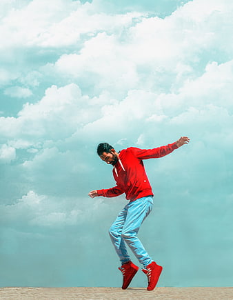 Man in Red Hoodie Dancing Against Cloudy Sky