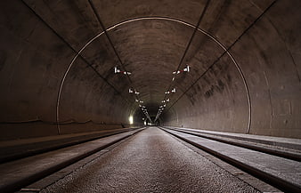 Perspective view of empty concrete tunnel with tracks and lights