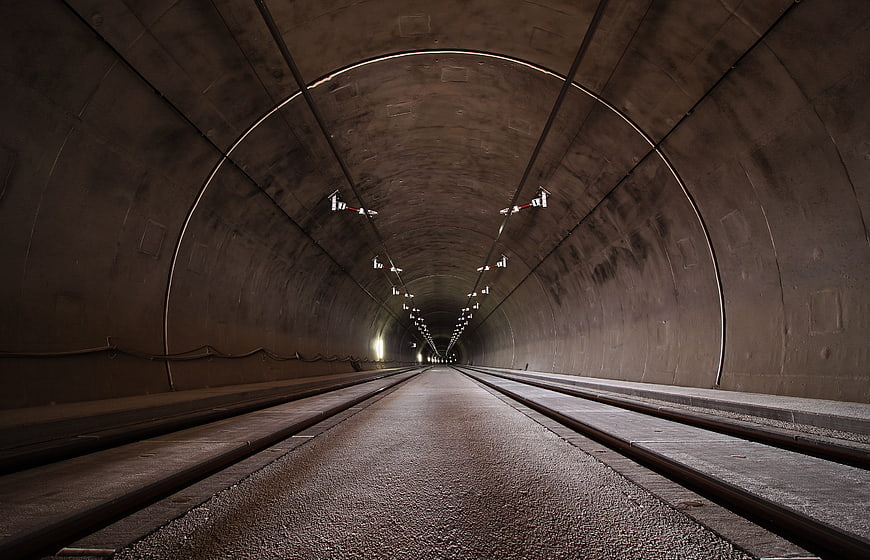 Perspective view of empty concrete tunnel with tracks and lights