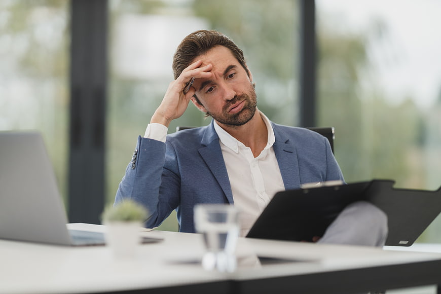 Stressed businessman holding head in hand at office desk