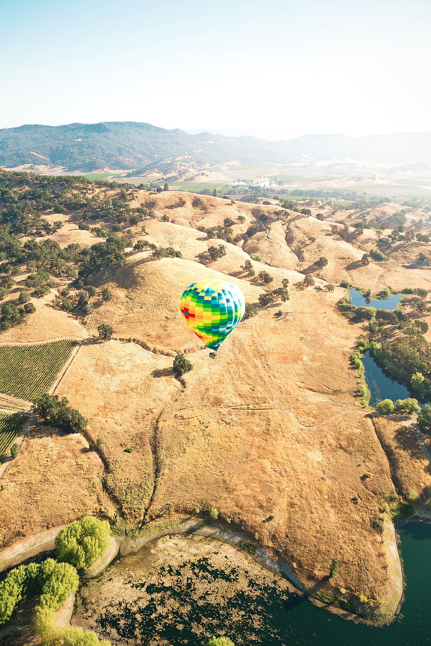 Aerial View of Colorful Hot Air Balloon Over Golden Hills