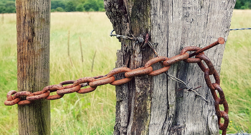 Rusty Chain and Barbed Wire on Weathered Wooden Fence Post
