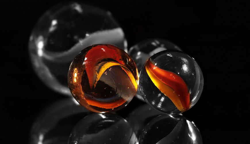 Colorful glass marbles on black reflective surface