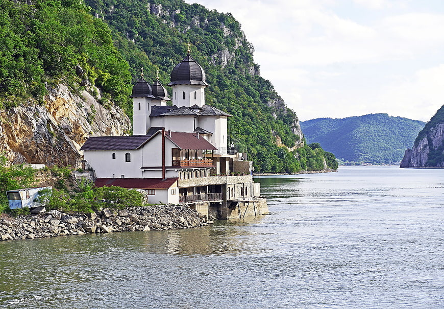 Orthodox Monastery on Danube River Bank with Mountain Backdrop