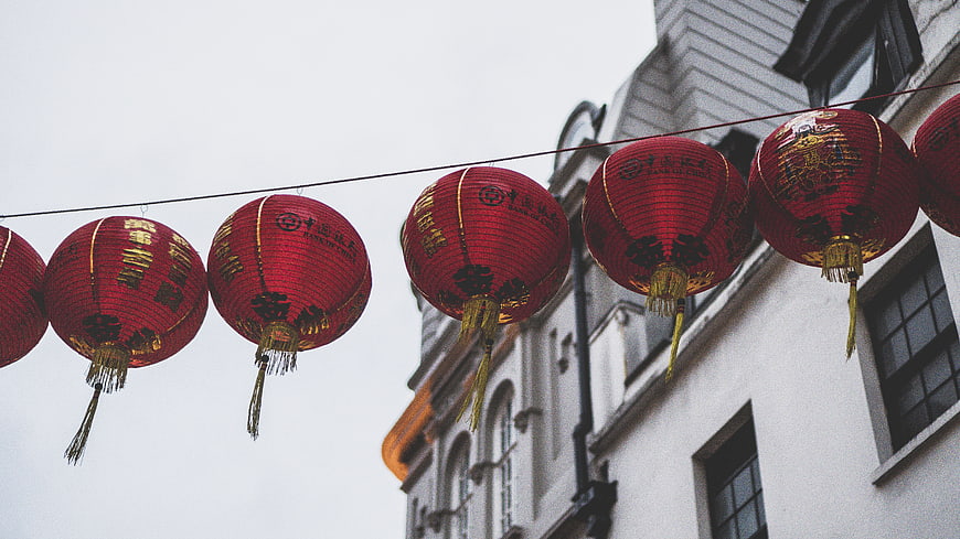 Red Chinese Lanterns Hanging on Wire Against White Building