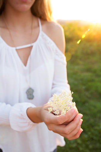 Woman holding white flowers in golden sunlight