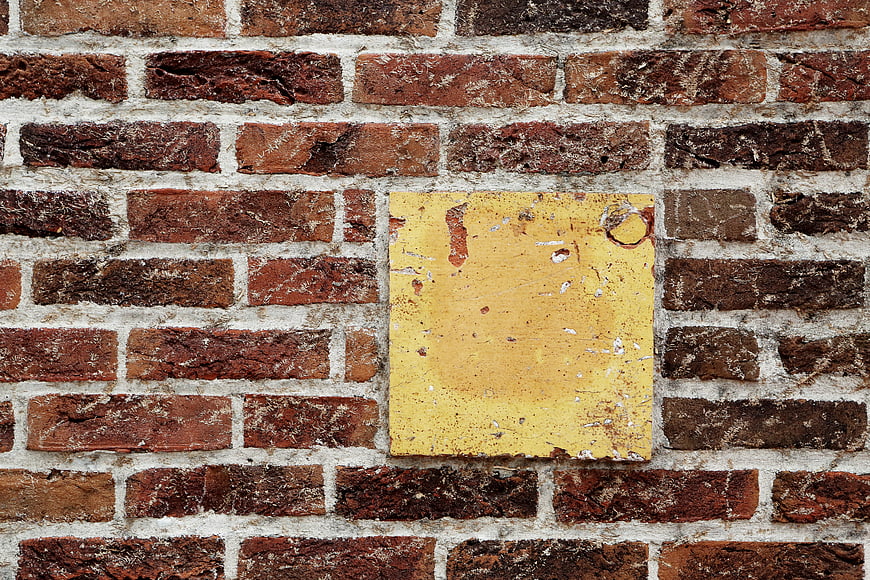 Weathered yellow square tile on old red brick wall texture