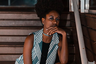 Stylish Woman with Afro Hair Sitting on Wooden Stairs