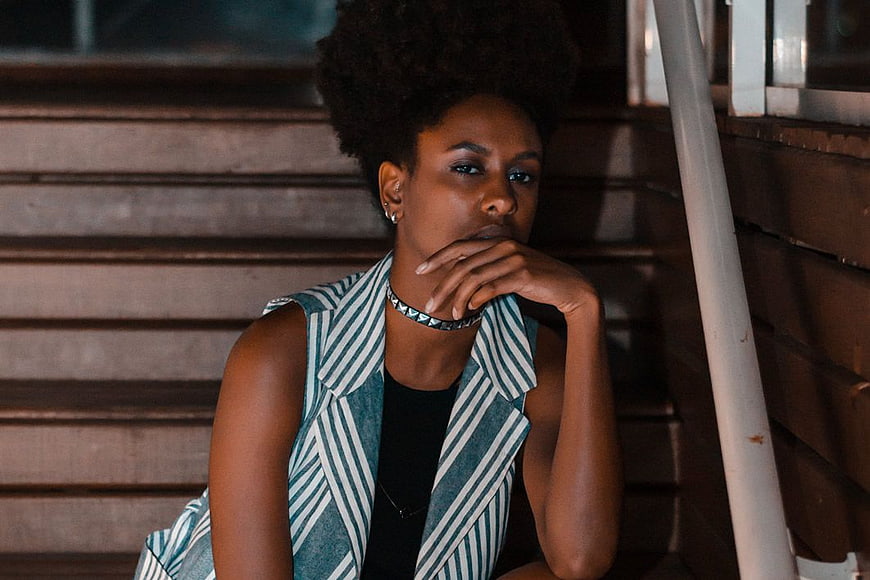 Stylish Woman with Afro Hair Sitting on Wooden Stairs
