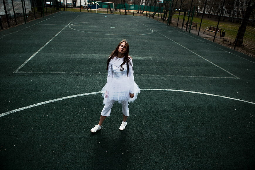 Woman in White Dress on Empty Basketball Court