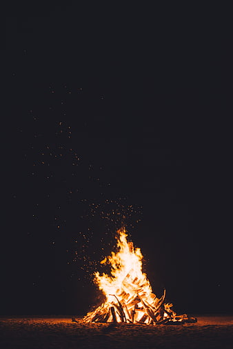Bonfire on sandy beach at night with sparks