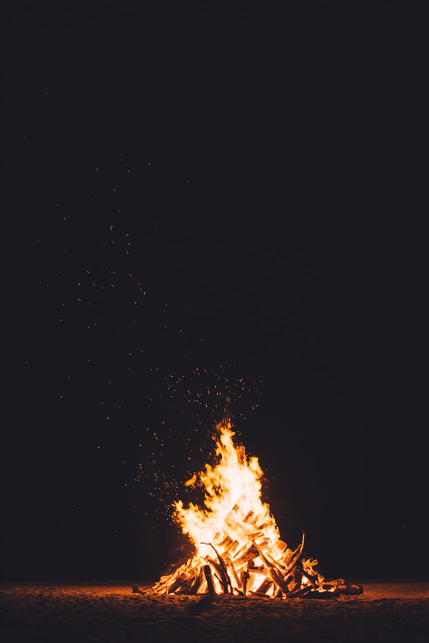 Bonfire on sandy beach at night with sparks