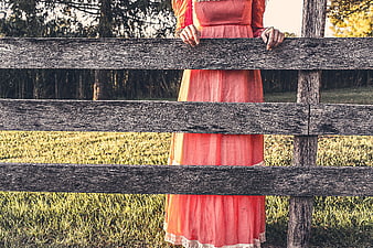 Woman in Pink Dress Behind Rustic Wooden Fence