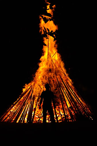 Silhouette of Man Standing Before Giant Bonfire at Night