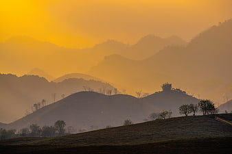 Golden Hazy Mountain Landscape with Silhouetted Hills