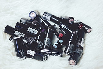 Collection of black lipstick tubes on white fur background