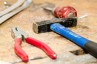 Close-up of used hammer and pliers on wooden workbench