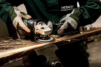 Worker grinding metal with angle grinder creating sparks