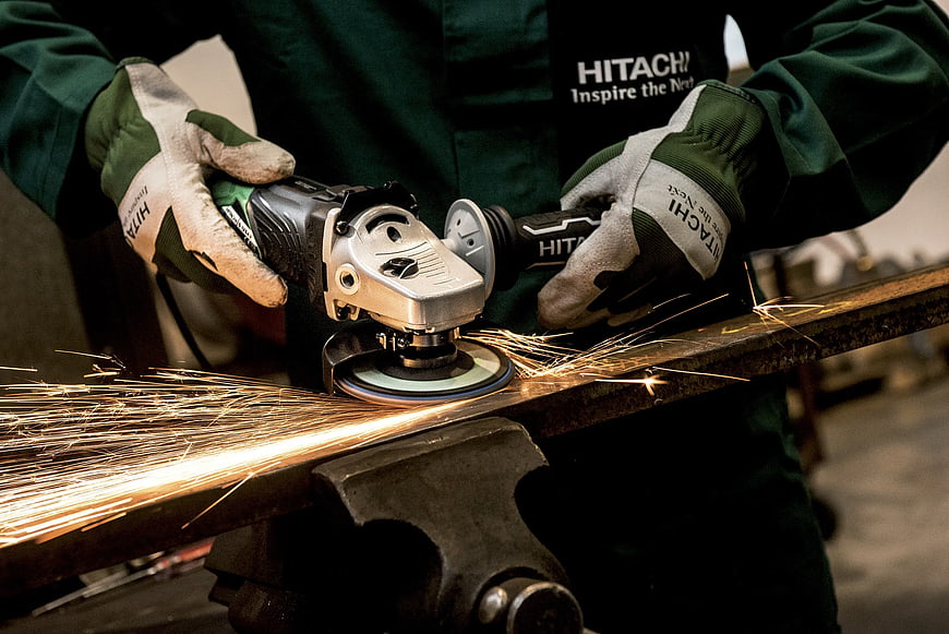 Worker grinding metal with angle grinder creating sparks