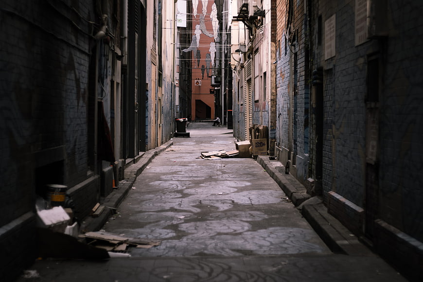 Narrow Urban Alleyway With Graffiti And Debris