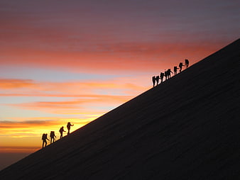 Silhouetted Mountaineers Climbing Slope at Sunrise
