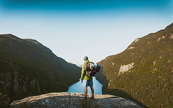 Hiker with Backpack Standing on Mountain Cliff Overlooking River