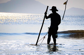 Silhouette of Fisherman with Spear in Shallow Beach Waters