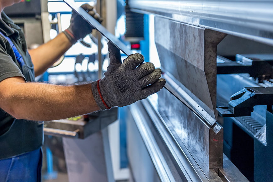 Worker operating metal bending machine in industrial factory