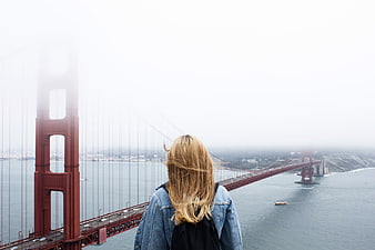Woman looking at foggy Golden Gate Bridge from behind