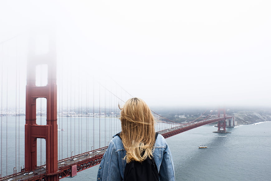 Woman looking at foggy Golden Gate Bridge from behind