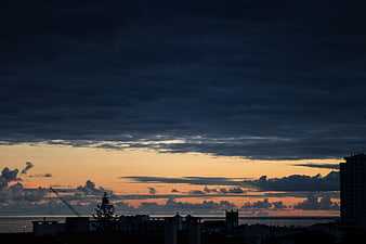 Dramatic sunset over coastal city skyline with clouds